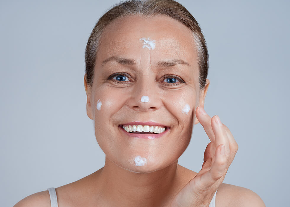 elderly woman moisturizing face.